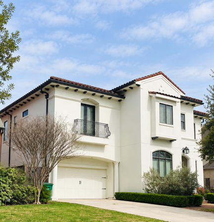 Two-story white stucco house with balcony and manicured lawn
